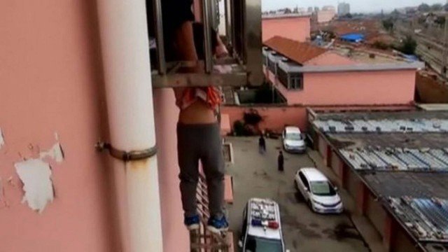 VÍDEO/ Bombeiros resgatam criança pendurada pelo pescoço em janela na China